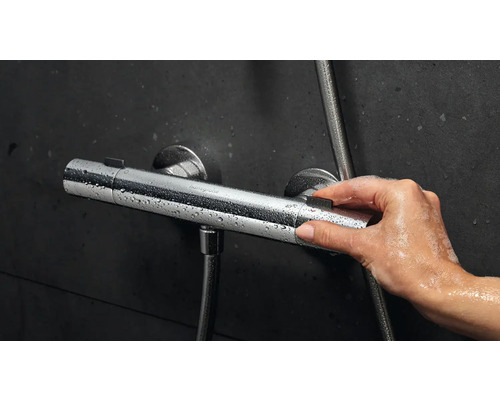 Imagine cu o mână care operează un termostat de duș