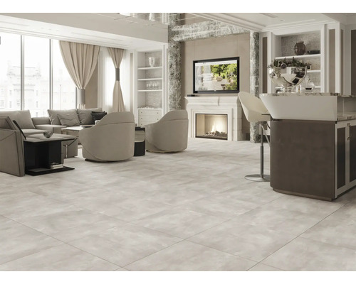 Cameră de zi luminoasă cu canapea, fotolii, televizor și podea cu gresie.