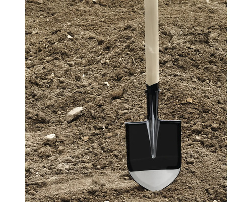 Cazan cu mâner de lemn într-un morman de pământ