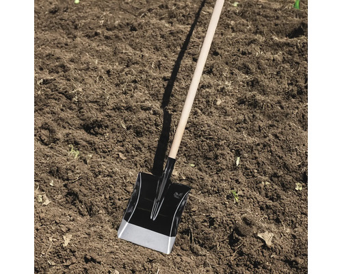 Cazan cu mâner de lemn în stratul de grădină