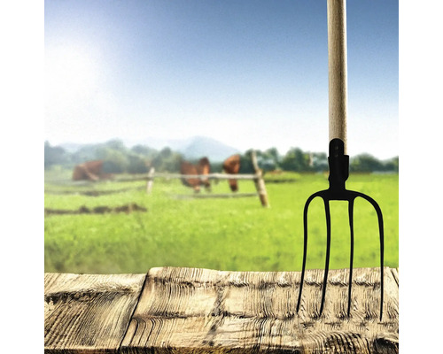 Furcă de fân metalică cu mâner din lemn pe masă din lemn