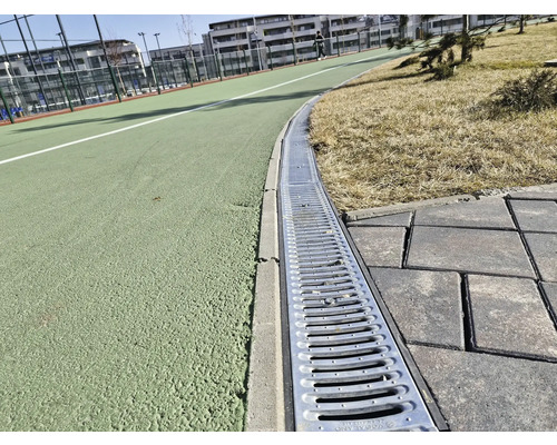 Imagine detaliată a unui sistem de canalizare lângă o alee și un teren de sport