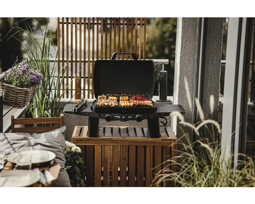 Scenă de balcon cu un grătar pe gaz și preparate culinare.