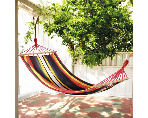 Hamac din material textil cu dungi, cu bară de susținere din lemn, atârnată în grădină.