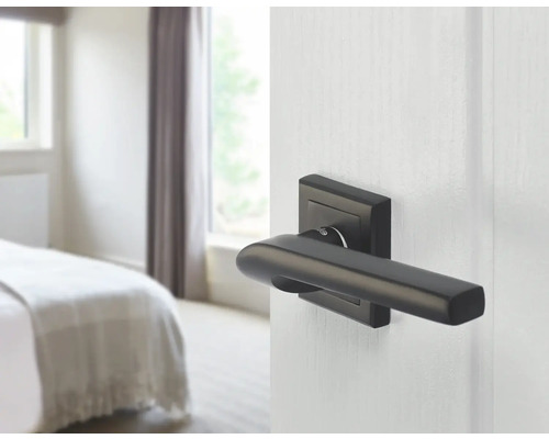 Ușă cu mâner modern și dormitor în fundal