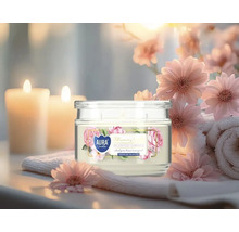 Lumânare parfumată în pahar cu motiv floral, înconjurată de decorațiuni