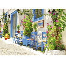 Alee luminoasă cu scaune vopsite în albastru, mese și jardiniere în fața unui zid alb