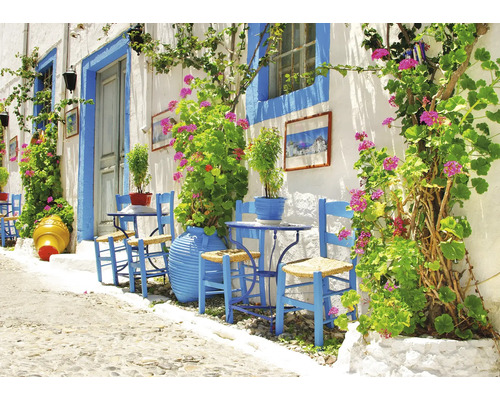 Alee luminoasă cu scaune vopsite în albastru, mese și jardiniere în fața unui zid alb