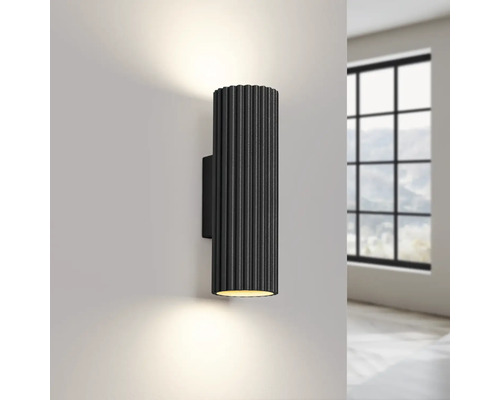 O lustră neagră de perete este montată pe un perete, emițând lumină în sus și în jos.