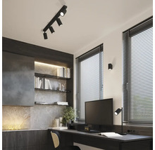 Spațiu de birou cu birou, rafturi și spot negru pe șină pe tavan.