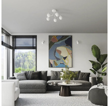 Living cu canapea, masă, operă de artă și plantă de apartament sub o lampă de tavan