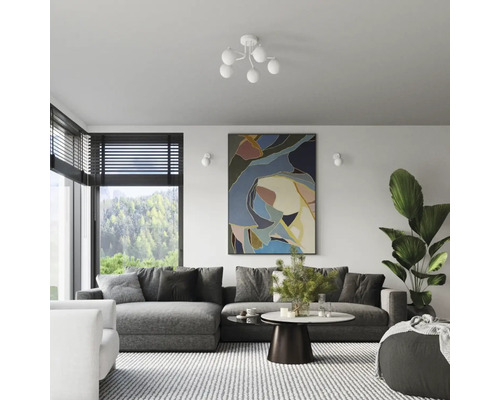 Living cu canapea, masă, operă de artă și plantă de apartament sub o lampă de tavan