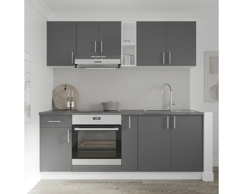 Bucătărie gri cu chiuvetă, aragaz și dulapuri suspendate.