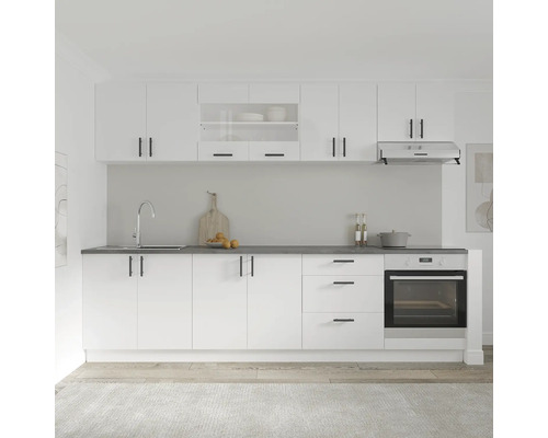 Bucătărie luminoasă cu dulapuri albe, blat de lucru negru și cuptor încorporat.