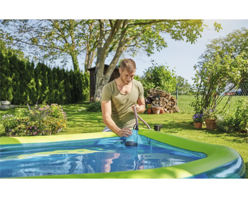 Un bărbat folosește o pompă submersibilă pentru a scoate apa dintr-o piscină din grădină.