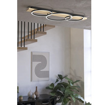 Interior modern cu o plafonieră LED cu trei inele, o scară și obiecte decorative.