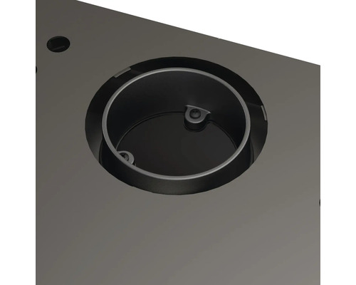 Prim-plan cu o inserție metalică rotundă într-un blat de masă