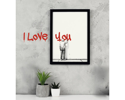 Imagine înrămată cu inscripția Te iubesc, lângă care se află două plante mici în ghiveci