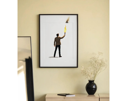Poster înrămat cu un bărbat cu o torță pe perete deasupra unei mese