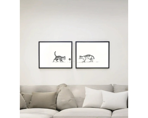 Două tablouri cu pisici înrămate atârnă deasupra unei canapele.