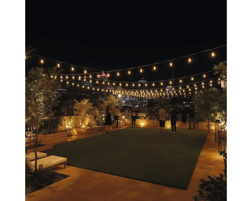 Decorarea unei terase pe acoperiș cu iluminare și gazon pe timp de noapte.