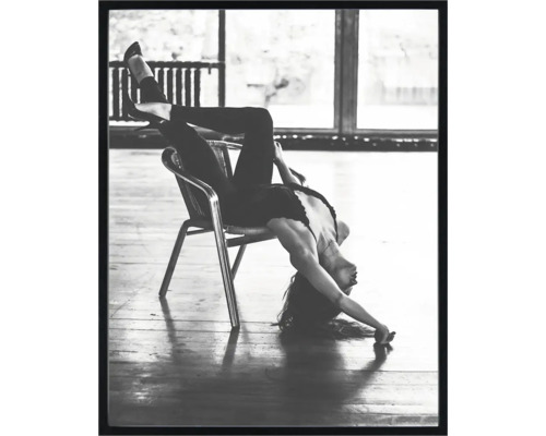 Fotografie alb-negru a unei femei așezate cu susul în jos pe un scaun