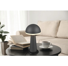 Lampă de masă cu design de ciupercă pe o masă cu o carte și o ceașcă