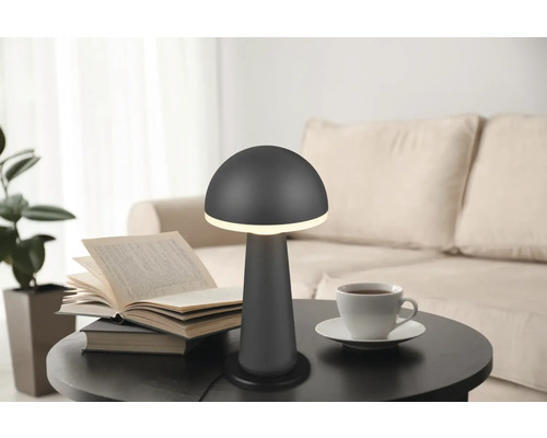 Lampă de masă cu design de ciupercă pe o masă cu o carte și o ceașcă