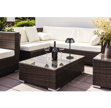 Scenă de exterior cu mobilier de ședere din ratan, măsuță de cafea cu blat de sticlă, sticlă de vin, pahare de vin și lampă de masă.