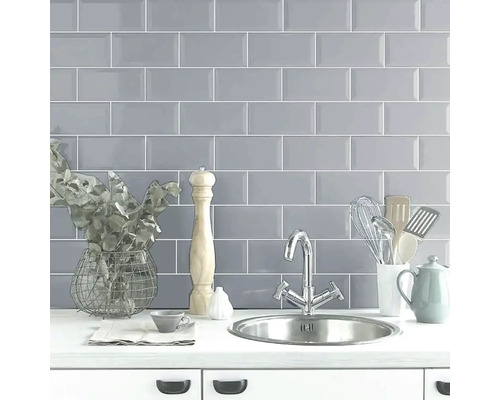 Scenă de bucătărie cu faianță gri, chiuvetă și ustensile de bucătărie.