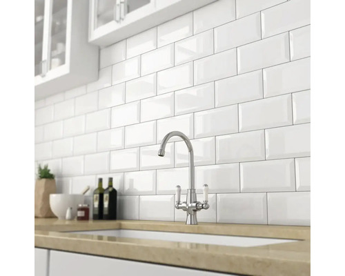 Scenă de bucătărie cu plăci de metro albe pe perete și robinet pe chiuvetă