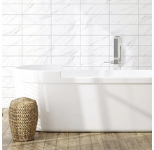 Baie modernă cu cadă freestanding, robinet, faianță cu aspect de marmură și taburet