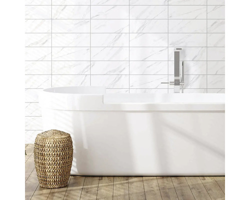 Baie modernă cu cadă freestanding, robinet, faianță cu aspect de marmură și taburet