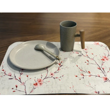 Farfurie, lingură și cană pe o față de masă cu model floral