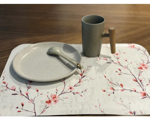 Farfurie, lingură și cană pe o față de masă cu model floral