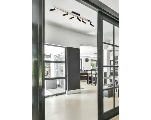 Imagine interioară a unui spațiu de locuit cu o ușă glisantă și o lampă de plafon cu mai multe spoturi.