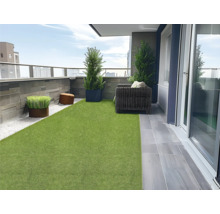 Balcon cu gazon artificial, jardiniere, scaune și pietre decorative pentru o atmosferă primitoare în aer liber.