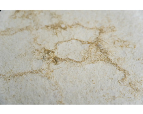 Prim-plan cu un blat de lucru de culoare deschisă cu marmorare maro