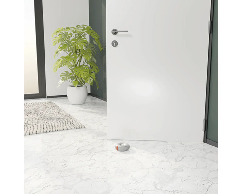 O ușă albă deschisă cu opritor de ușă gri pe o podea de marmură