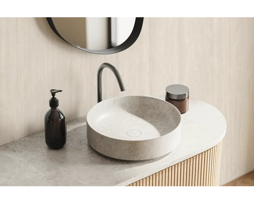 Mobilier de baie cu lavoar rotund, baterie, dozator de săpun și recipient pentru cosmetice.