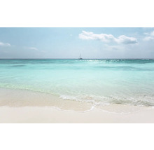 O plajă cu nisip fin, cu o mare turcoaz și o barcă cu pânze la orizont