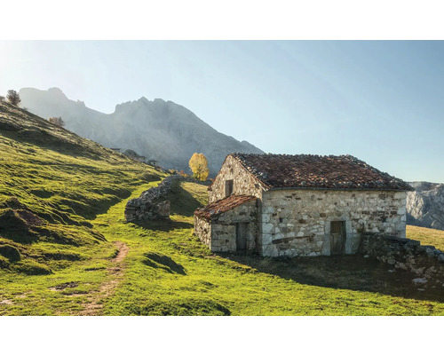 Casă de piatră într-un peisaj verde cu munți