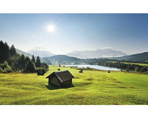 Peisaj cu pajiște, lac și cabane din lemn
