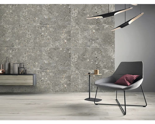 Perete de gresie gri cu aspect de terrazzo, combinat cu un fotoliu modern și mobilier minimalist