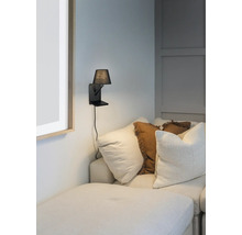Lampa de perete cu abajur mic lângă o canapea cu perne