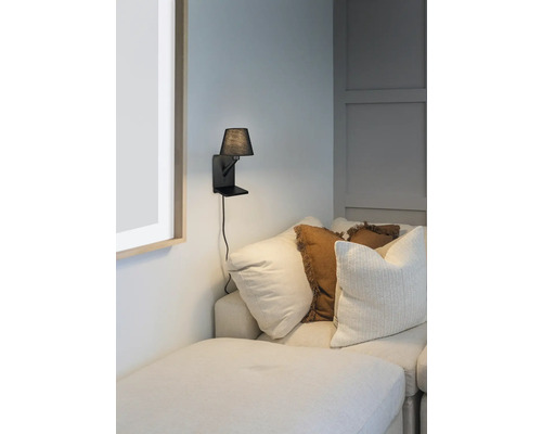 Lampa de perete cu abajur mic lângă o canapea cu perne