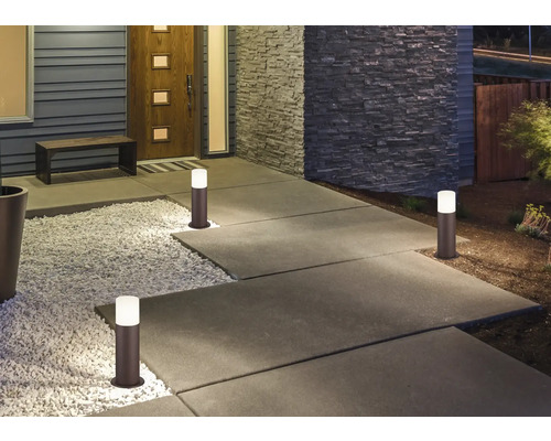 Alee iluminată cu mai multe lămpi tip baliză în fața unei case.