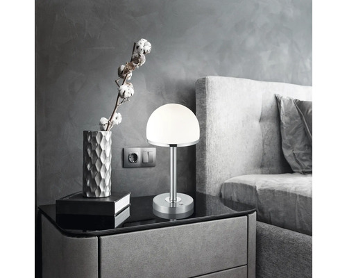 Noptieră cu lampă, decorațiuni și pat în dormitor