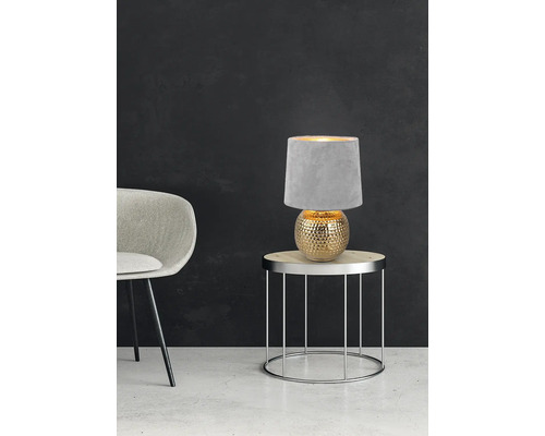 Lampă de masă decorativă cu abajur textil pe o măsuță laterală lângă scaun