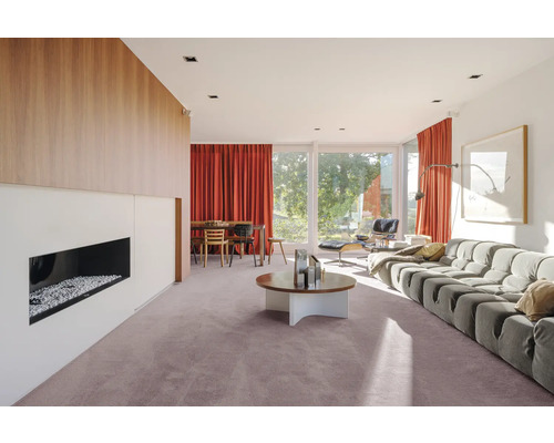 Cameră de zi luminoasă cu șemineu, fereastră mare și mobilier modern.